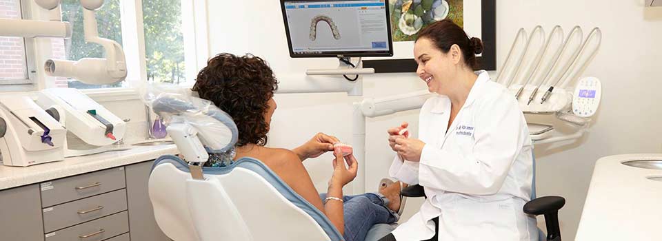 dentist showing patient a model of teeth and gums