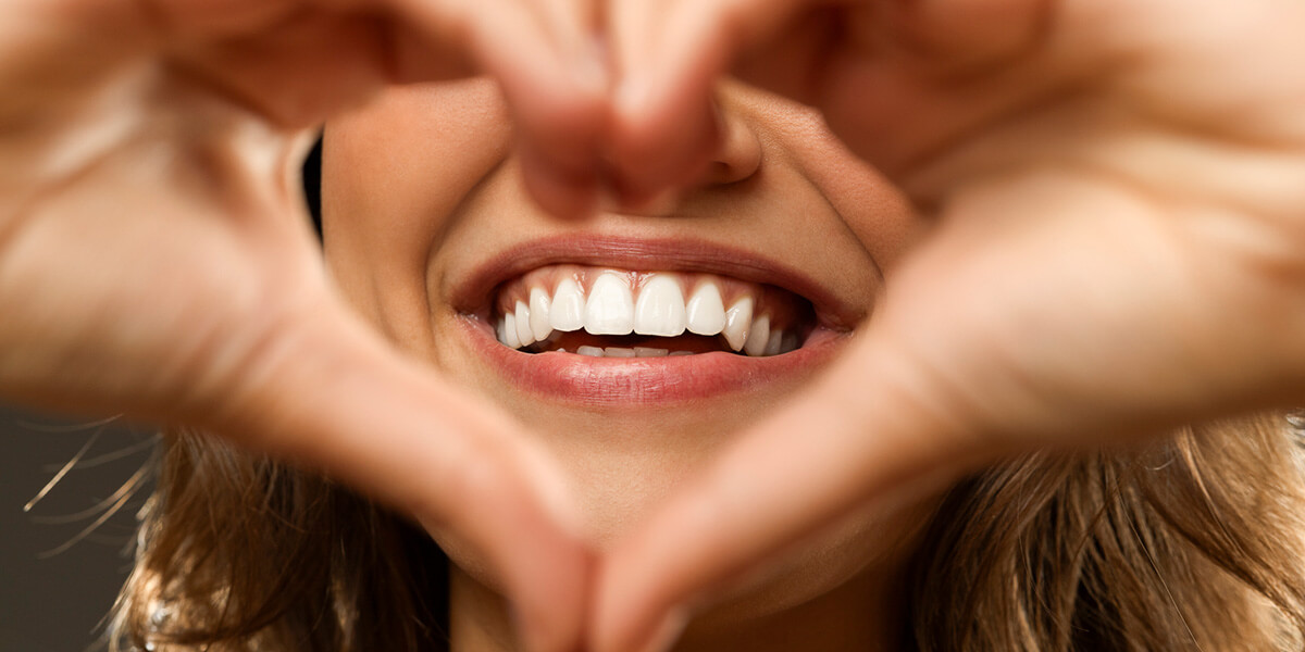 woman making heart hands around perfect smile